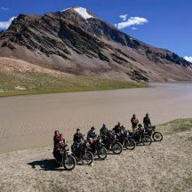 a group of people riding bikes on a dirt road near a mountain
