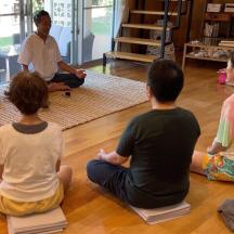 a group of people sitting on the floor in a yoga class