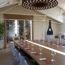Una mesa larga en una habitación con sillas y botellas de vino.