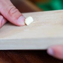 a person holding a piece of food on a cutting board