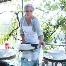 een vrouw die voor een tafel met servies staat