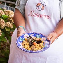 a woman holding a bowl of pasta in her hands