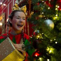 una noia jove que sosté un regal davant d'un arbre de Nadal