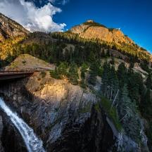 un pont sobre una cascada al costat d'una muntanya