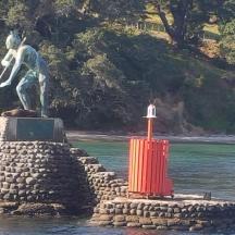 a statue of a man on a rock island in the water