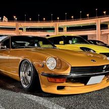 two yellow cars parked in a parking lot at night