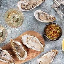 a table with a plate of oysters and glasses of wine