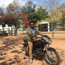 a man sitting on a motorcycle on a dirt road