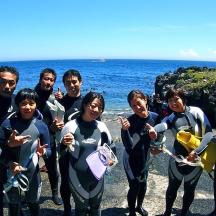 a group of people in wet suits standing next to the ocean