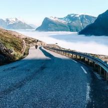 a person is walking down a road in the mountains