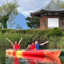 tiga orang dalam kayak di atas air berhampiran pagoda