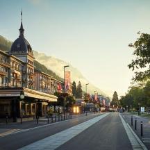 an empty city street with buildings and a mountain