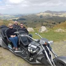 a group of three people sitting on a motorcycle