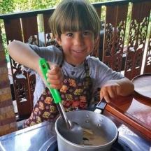 a young child stirring a pot with a spoon