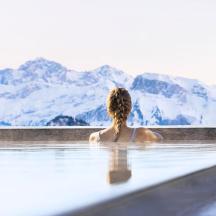 a woman sitting in a bath tub looking at mountains