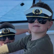 two young boys wearing sunglasses and a captain hat