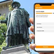una persona che tiene in mano un telefono cellulare davanti a una statua