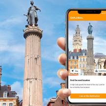 una persona sostenint un telèfon mòbil davant d'una estàtua