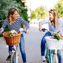 two girls riding bikes with flowers in their baskets