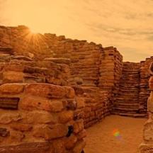 a stone wall with the sun setting behind it