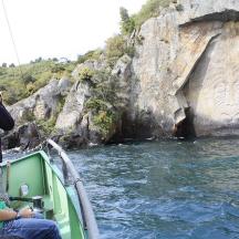 two people on a boat in front of a rock formation