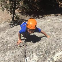 オレンジ色のヘルメットをかぶって砂場で遊ぶ少年