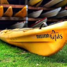 a yellow kayak sitting on the grass next to a group of boats