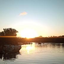 a boat on a river with the sun setting