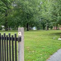 a fence in a park with a field and trees