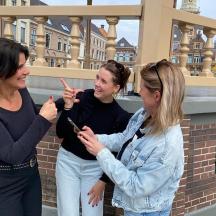 three women standing next to each other looking at their cell phones