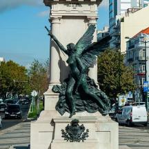 a statue of a woman on a pole on a city street