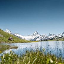 a couple of people sitting next to a lake
