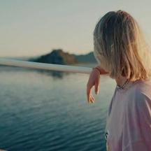 una giovane ragazza in piedi su una barca vicino all'acqua