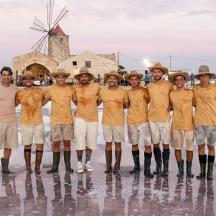 a group of people wearing orange shirts standing in front of a windmill