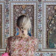 una dona amb una bossa rosa mirant una paret
