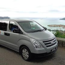 a silver van parked on a road near the ocean