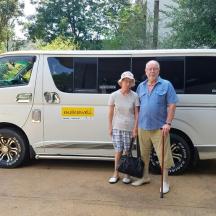an older man and woman standing in front of a van