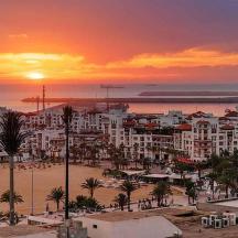 a sunset over a city with a beach and buildings