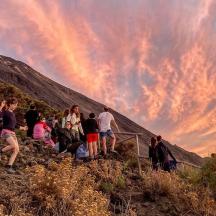 eine Gruppe von Menschen steht bei Sonnenuntergang auf einem Hügel