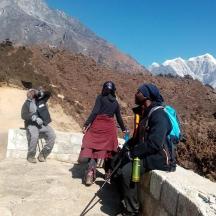 a group of people standing on a wall on a mountain