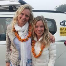 two women standing in front of a white van