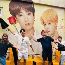 a group of people standing in front of a mural