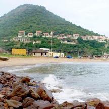 a beach with rocks and a mountain in the background