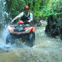 a man riding a atv through a waterfall