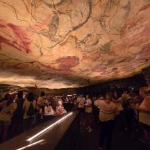eine Gruppe von Menschen in einer Höhle mit einem Gemälde an der Wand