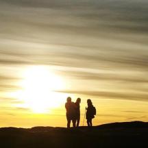 zwei Menschen stehen bei Sonnenuntergang auf einem Hügel