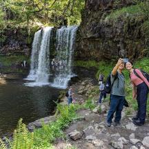 ein Mann, der ein Foto von einem Wasserfall macht