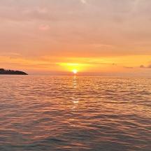 un tramonto su uno specchio d'acqua con il sole che tramonta