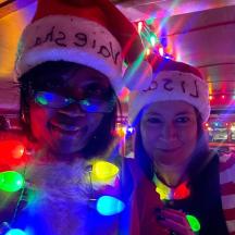 zwei Frauen mit Weihnachtsmannmützen in einem Raum mit Lichtern