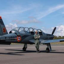 a man standing next to a fighter plane on a runway